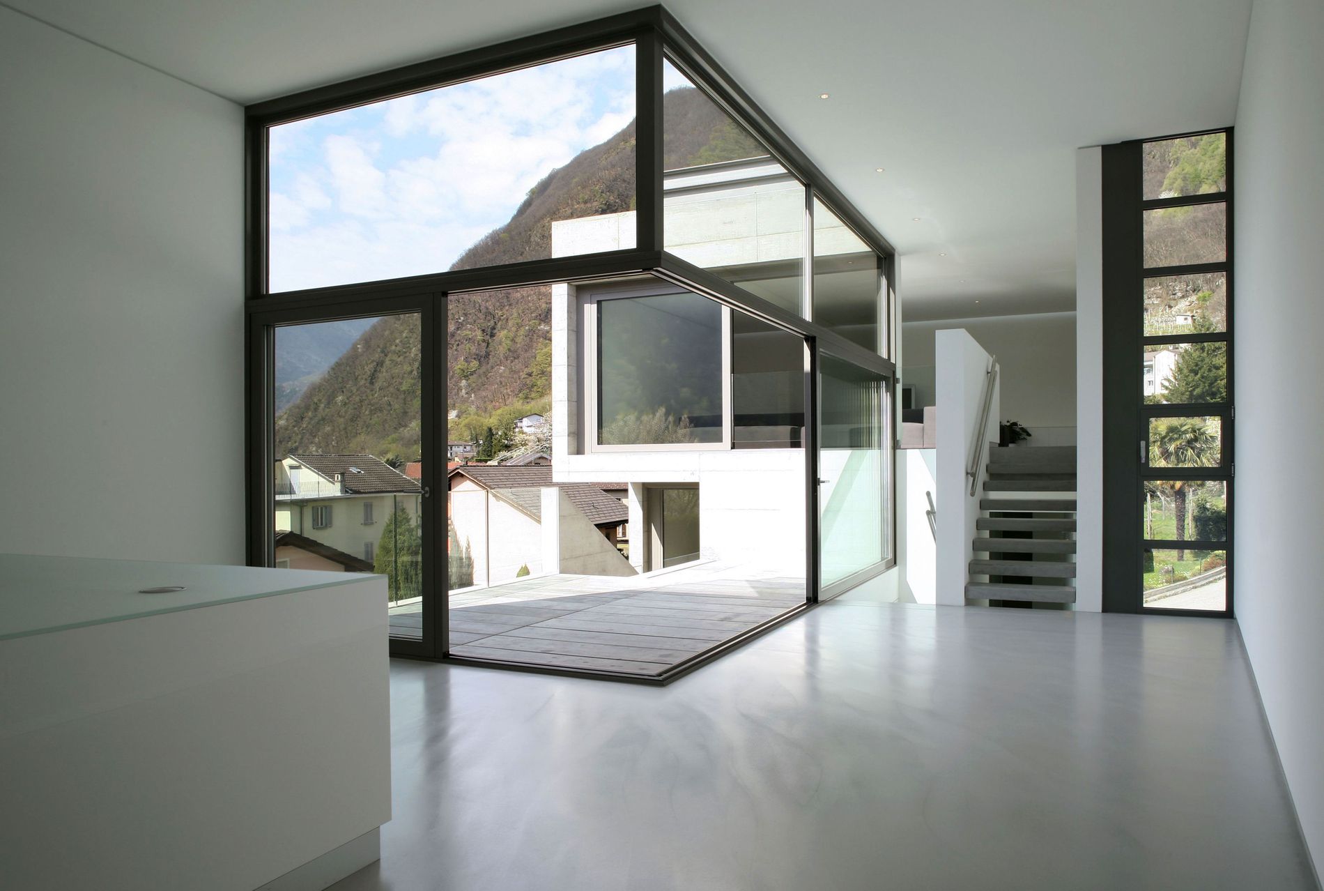 Moderner, leerer Raum mit großen Glasfenstern und Blick auf Berglandschaft